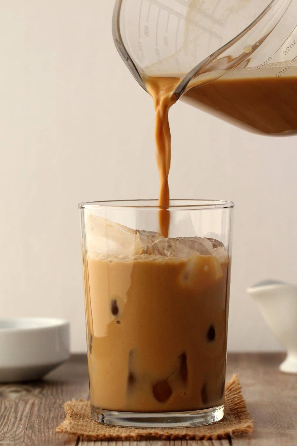 Vegan Iced Coffee pouring into a glass full of ice. 