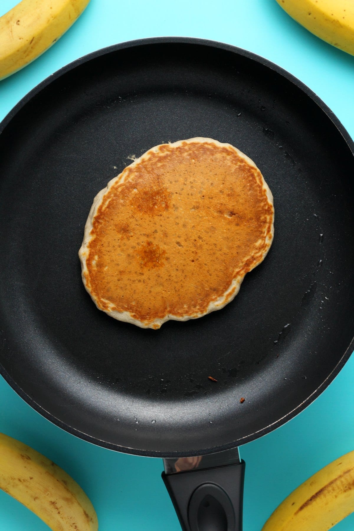A vegan banana pancake cooking in a frying pan. 