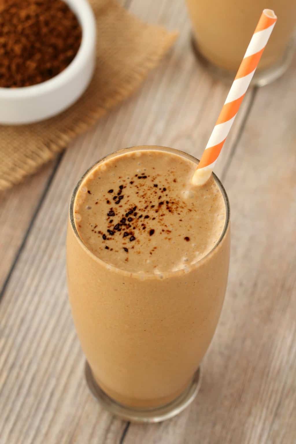 Vegan Coffee Smoothie in a glass with an orange and white striped straw.