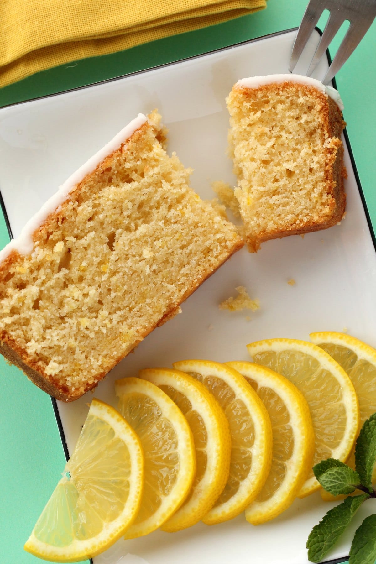 A slice of vegan lemon pound cake on a white plate with a cake fork. 