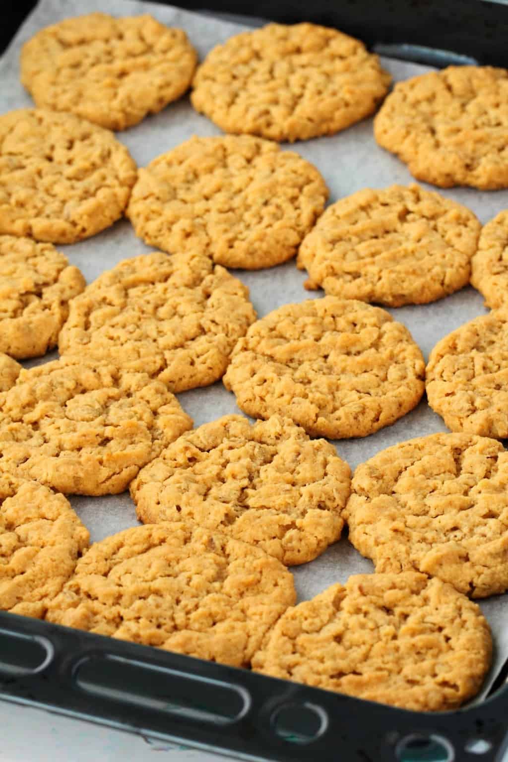 Freshly baked vegan peanut butter oatmeal cookies on a parchment lined baking tray. 