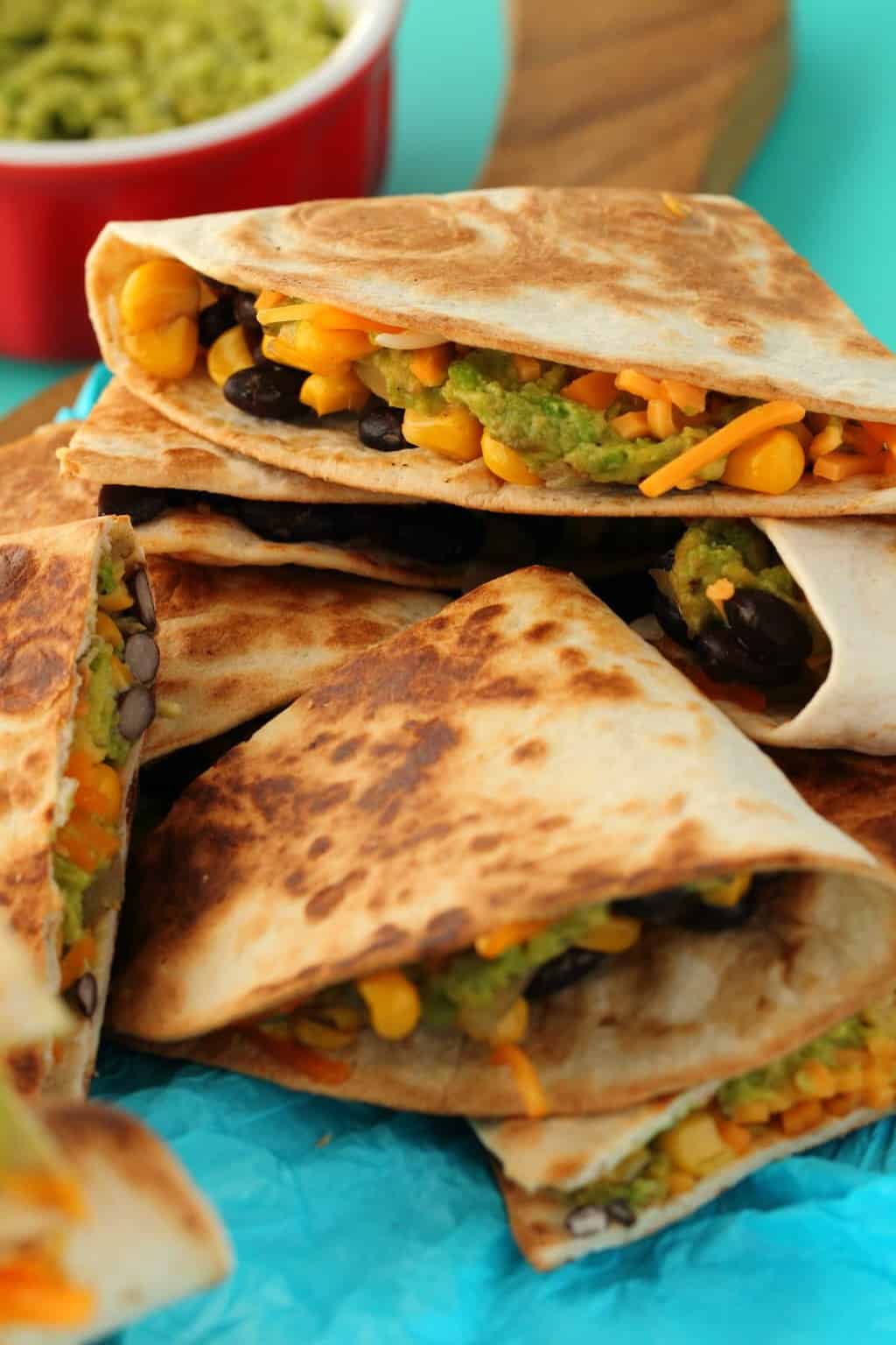 Vegan Quesadillas stacked on top of each other on a blue background. 