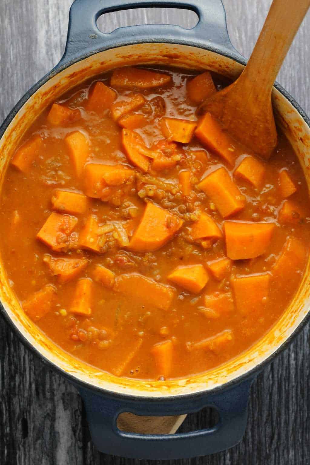 Vegan Sweet Potato Curry in a cast iron pot with a wooden spoon. 