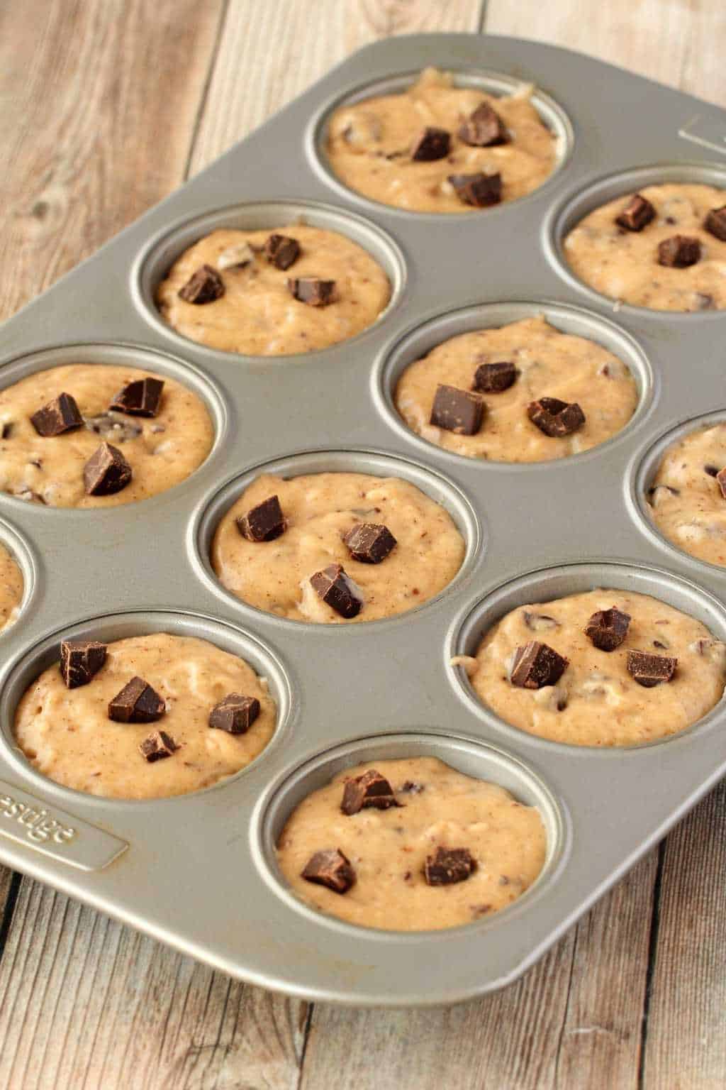 Vegan banana chocolate chip muffin batter in a muffin tray ready to go into the oven and bake.