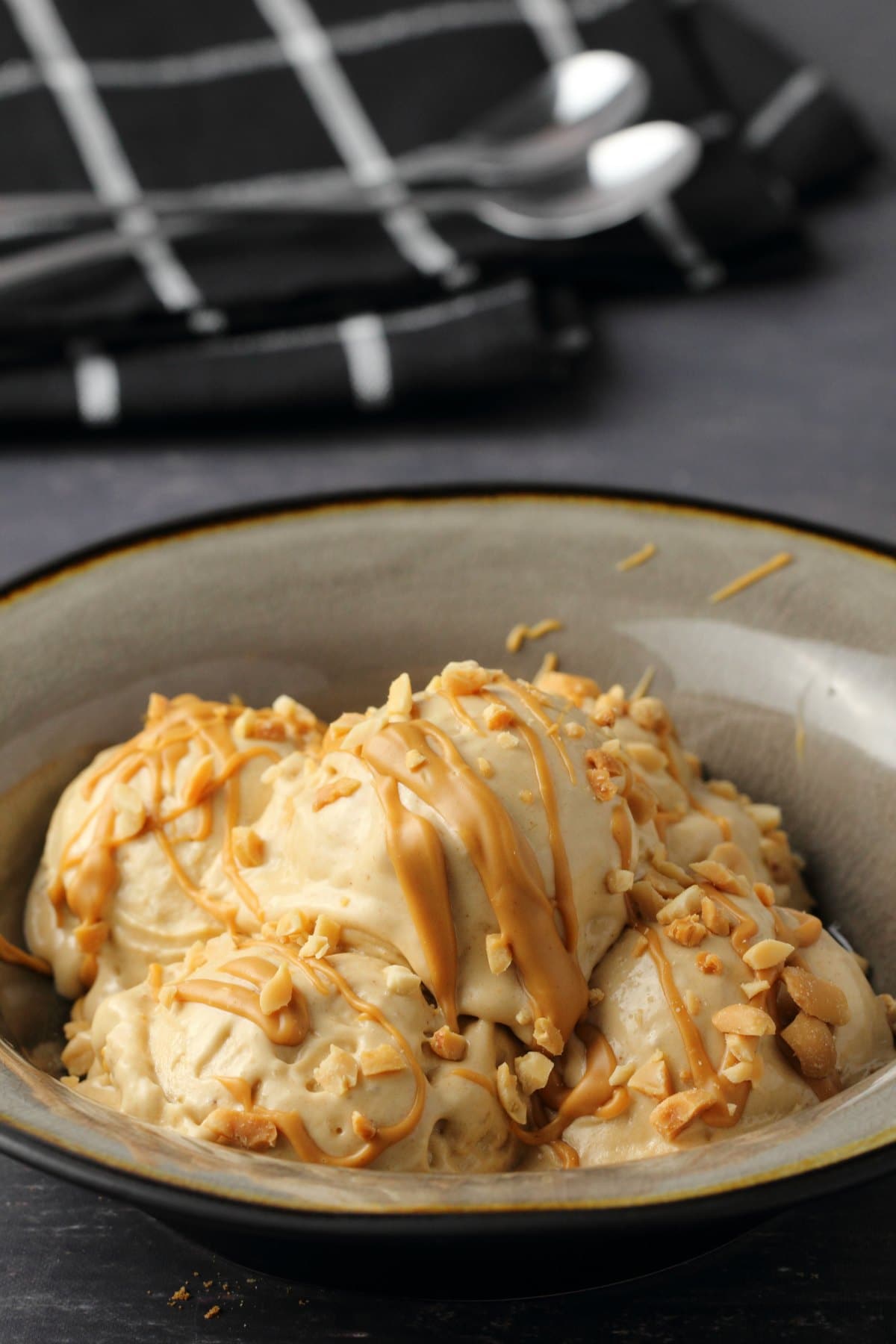 Peanut butter banana nice cream topped with drizzled peanut butter and crushed peanuts in a stone bowl. 