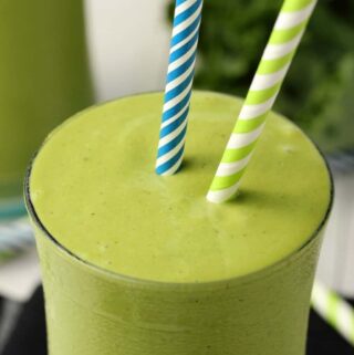 Kale Smoothie in a glass with straws.