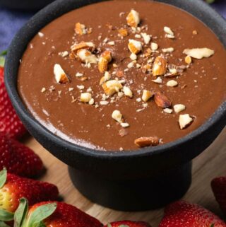 Chocolate hummus topped with almonds in a black bowl.