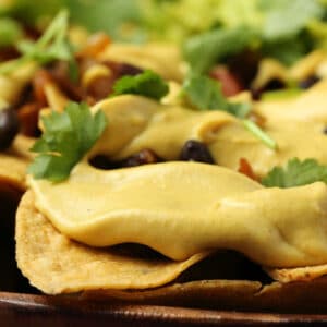 Vegan nacho cheese drizzled over a plate of nachos.