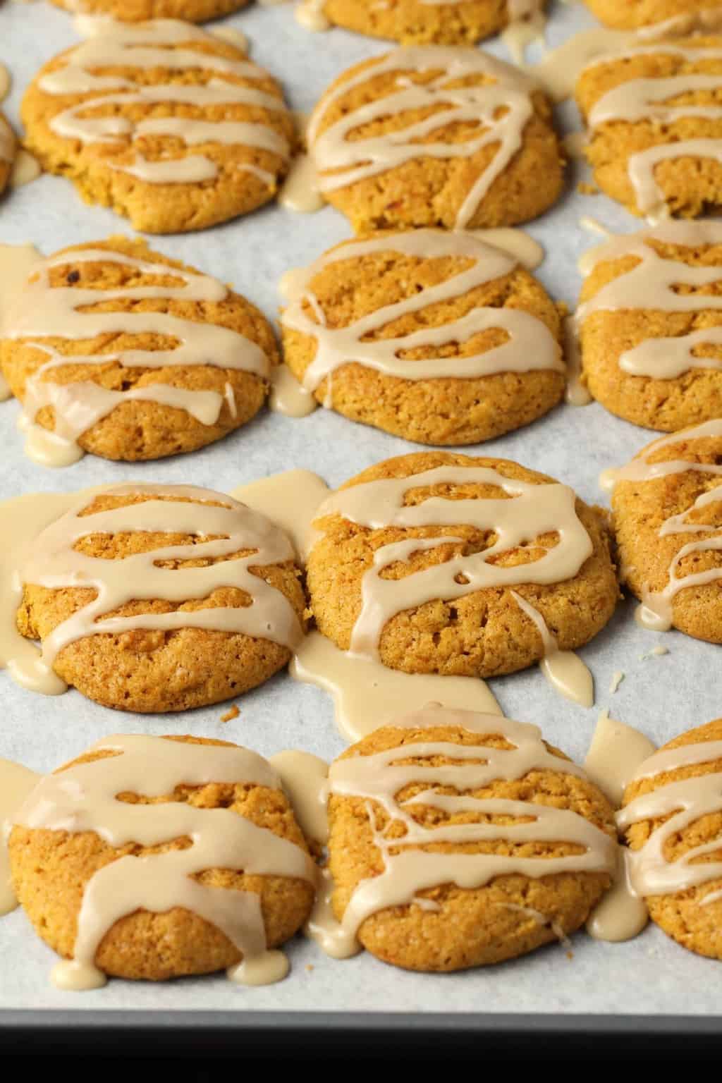 Vegan Pumpkin Cookies with a maple glaze on a parchment lined baking tray. 
