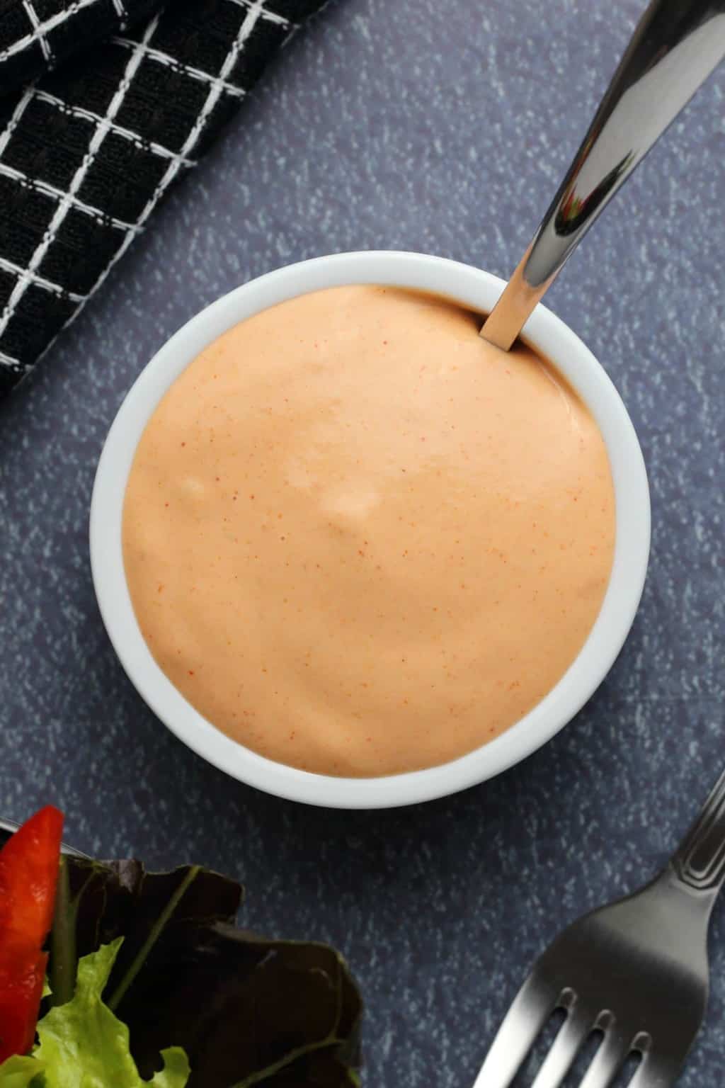Vegan thousand island dressing in a white bowl with a spoon. 