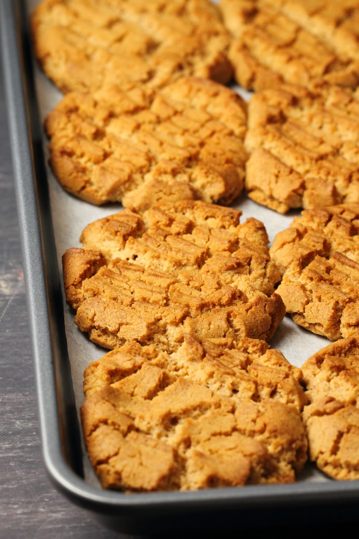 Freshly baked almond butter cookies on a parchment lined baking tray.