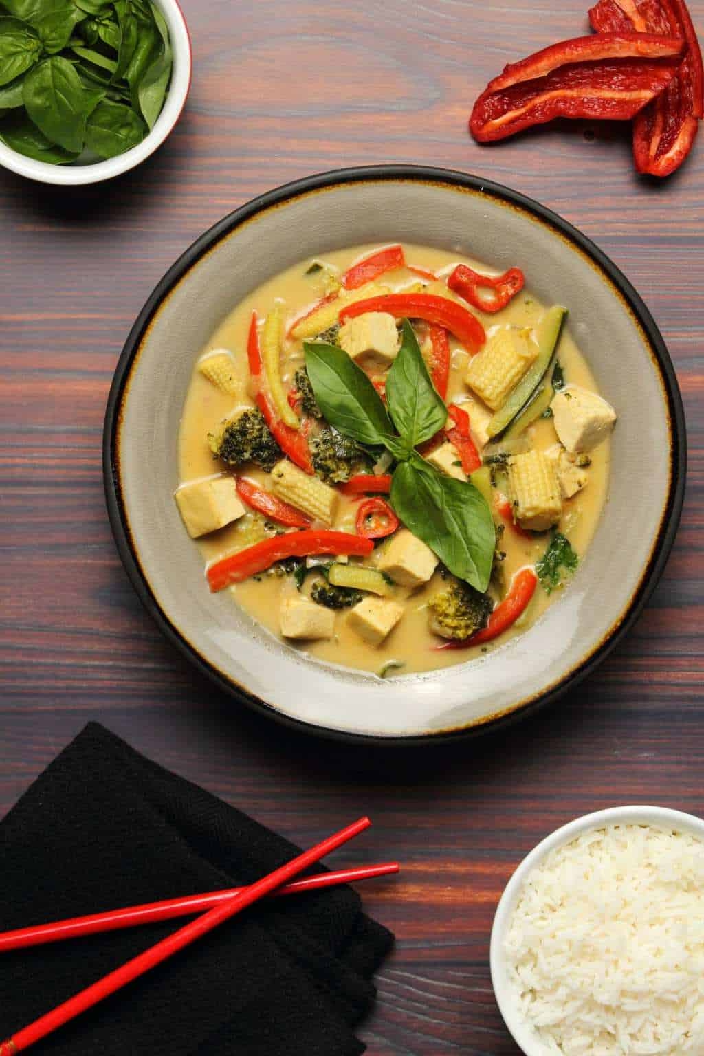 Vegan green curry topped with fresh basil in a stone bowl. 