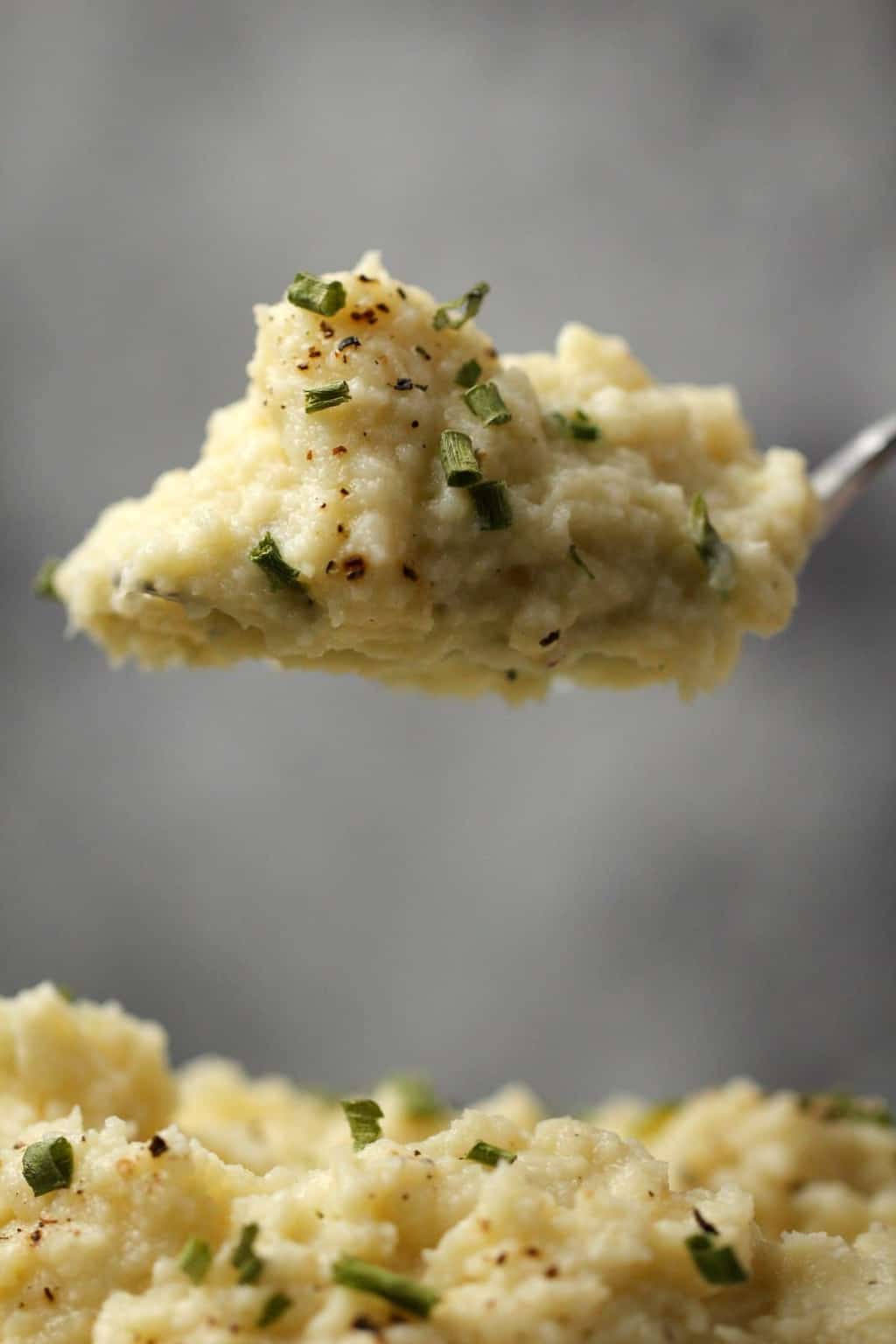 Spoonful of vegan cauliflower mashed potatoes with chopped chives.