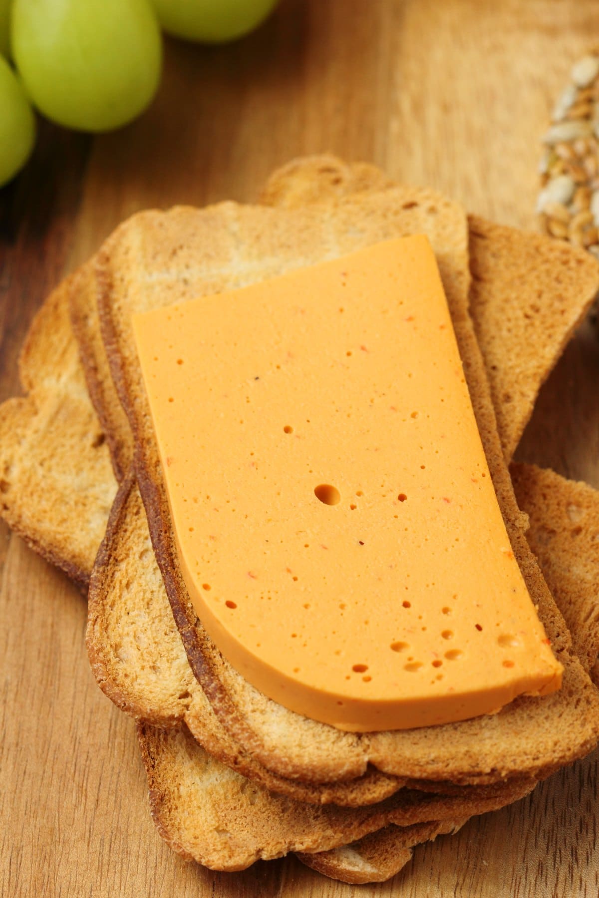 Slicesd vegan cheddar cheese on melba toast. 