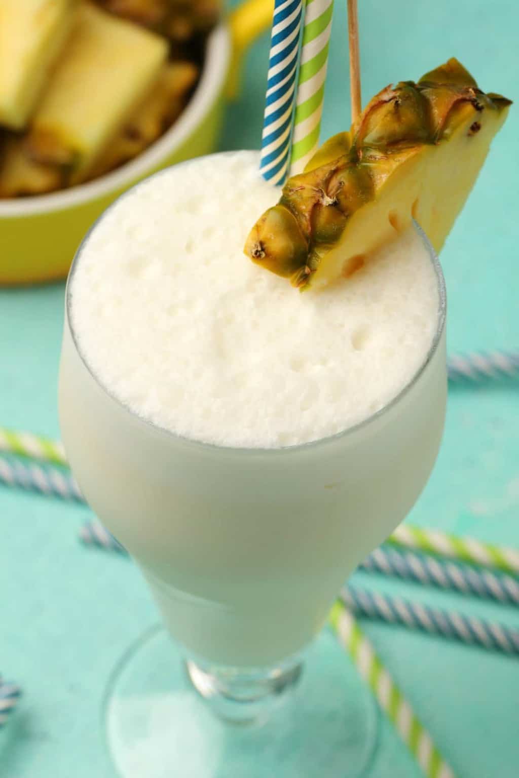Vegan pina colada in a glass with a pineapple slice and straws. 