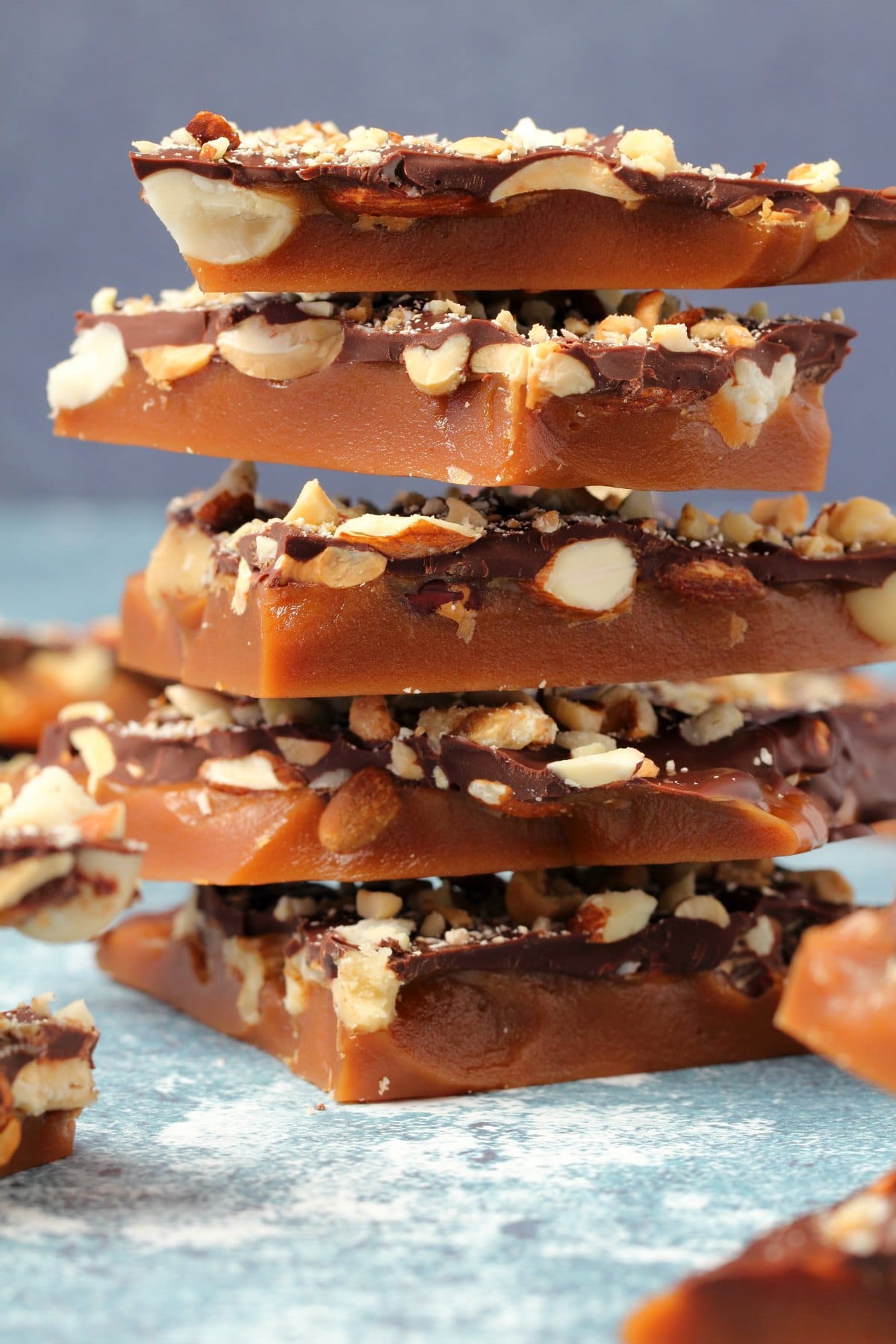 Vegan toffee topped with mixed nuts and chocolate in a stack. 