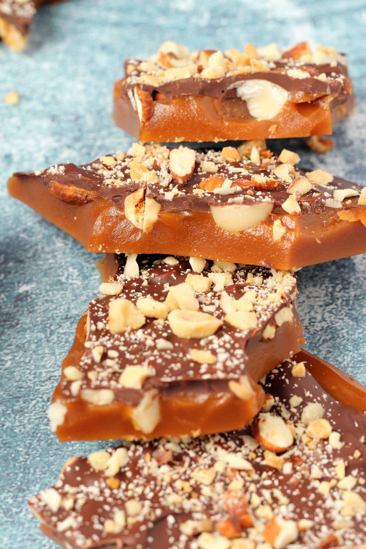 Pieces of vegan toffee topped with mixed nuts and vegan chocolate. 