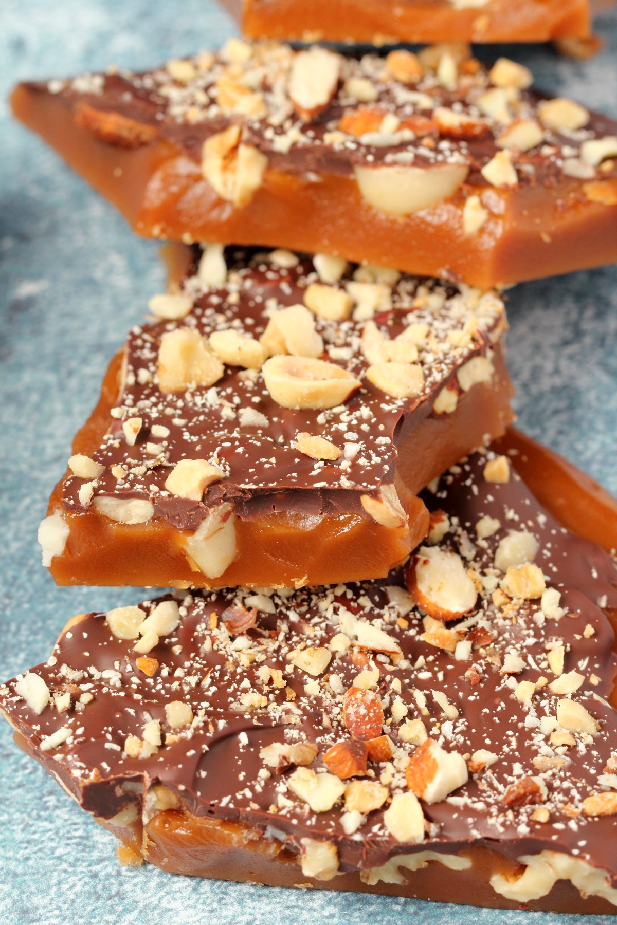Pieces of vegan toffee topped with mixed nuts and vegan chocolate. 