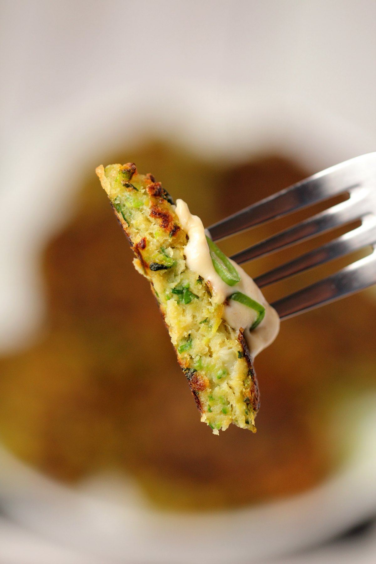 Slice of vegan zucchini fritter on the end of a fork. 