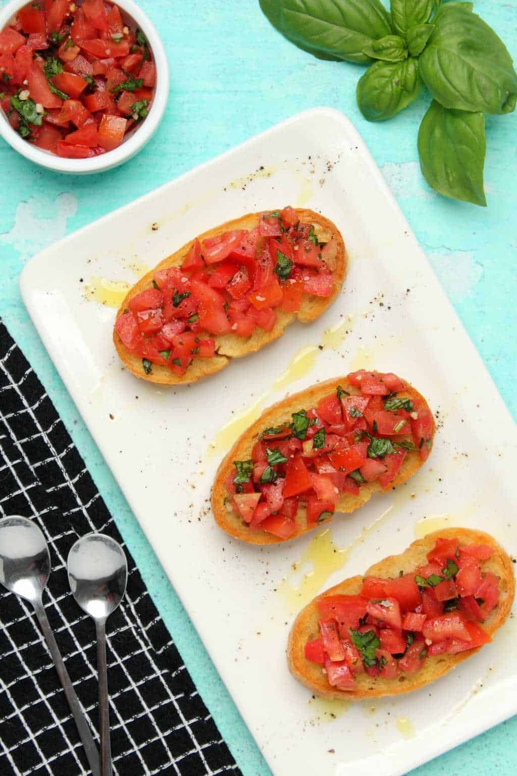Vegan bruschetta drizzled with olive oil on a white plate. 