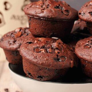 Vegan chocolate muffins stacked up in a white bowl.
