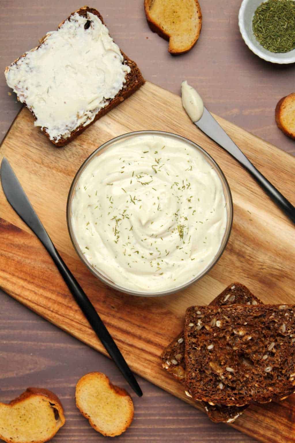 Vegan cream cheese topped with a sprinkle of dried drill in a glass dish. 