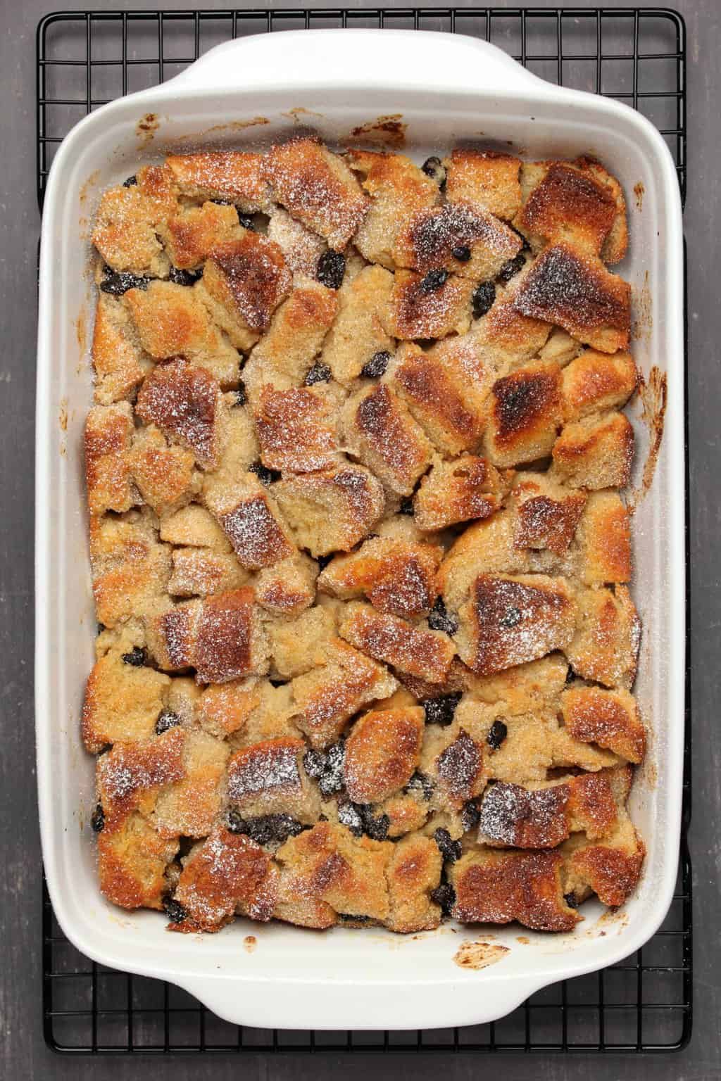 Vegan bread pudding freshly baked and topped with a dusting of powdered sugar. 