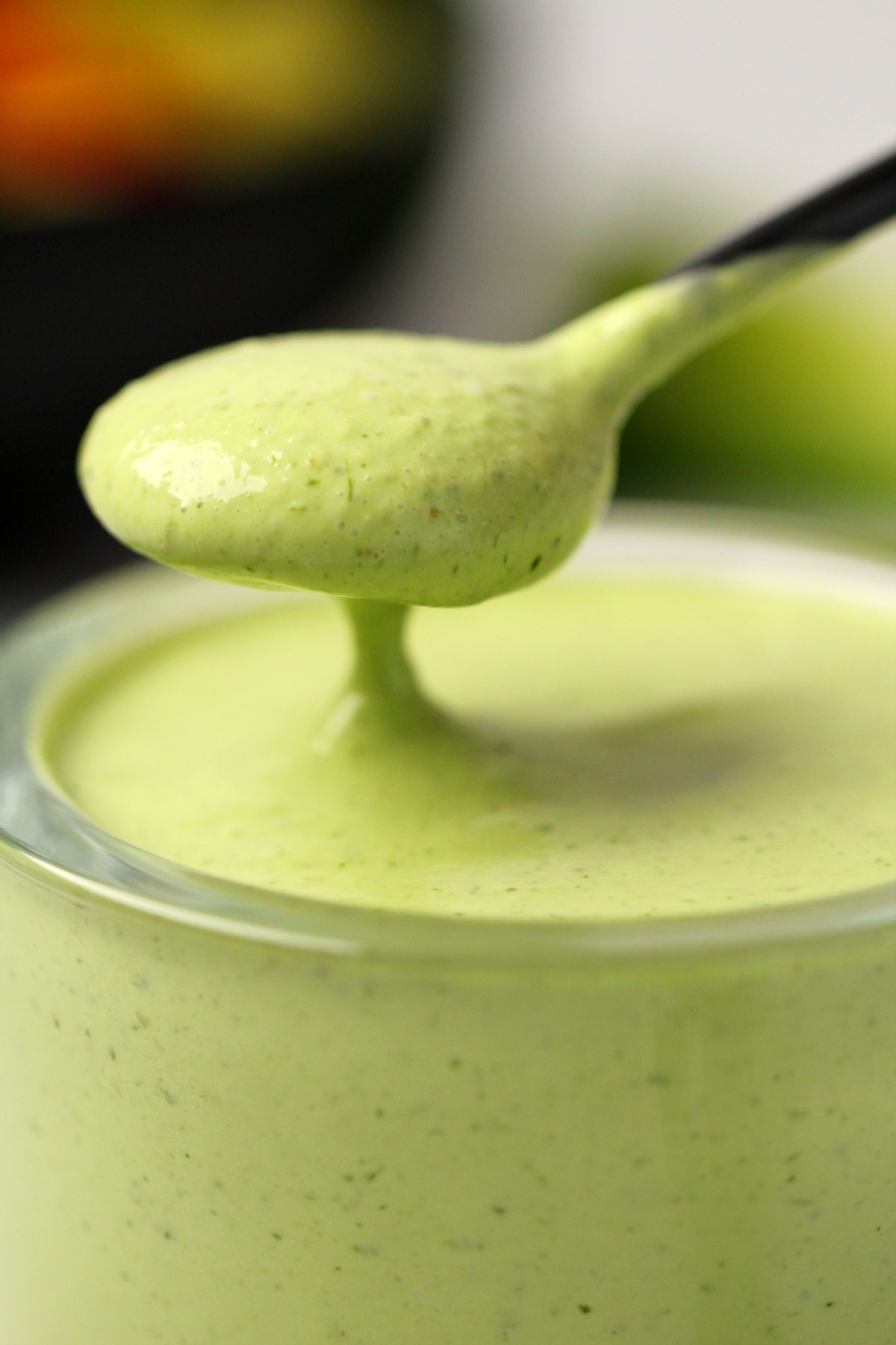 Vegan green goddess dressing in a glass jar with a spoon. 