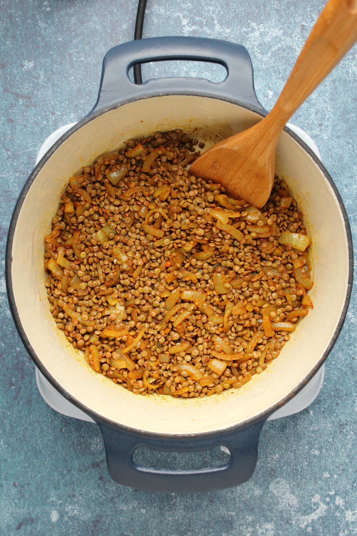 Lentils tossed with onions and spices in a pot. 