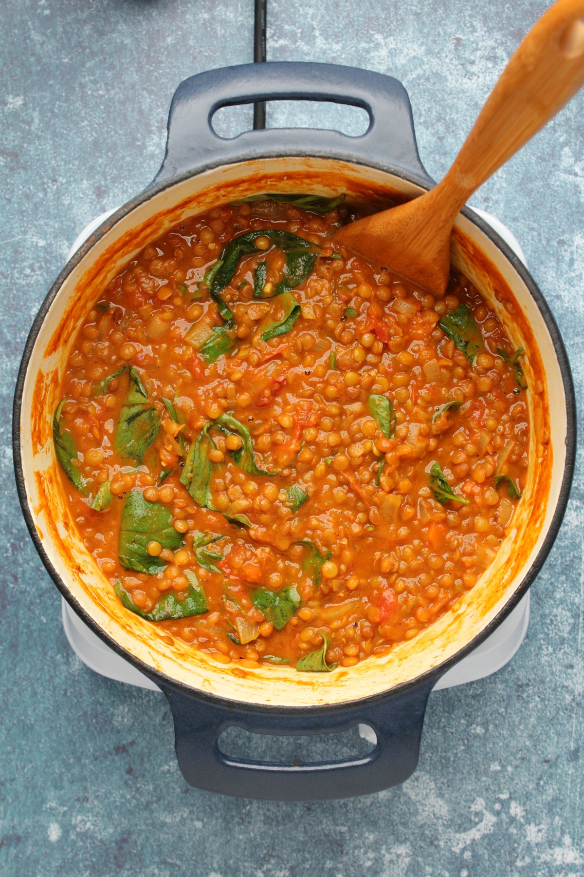 Lentil curry with wilted baby spinach in a pot.