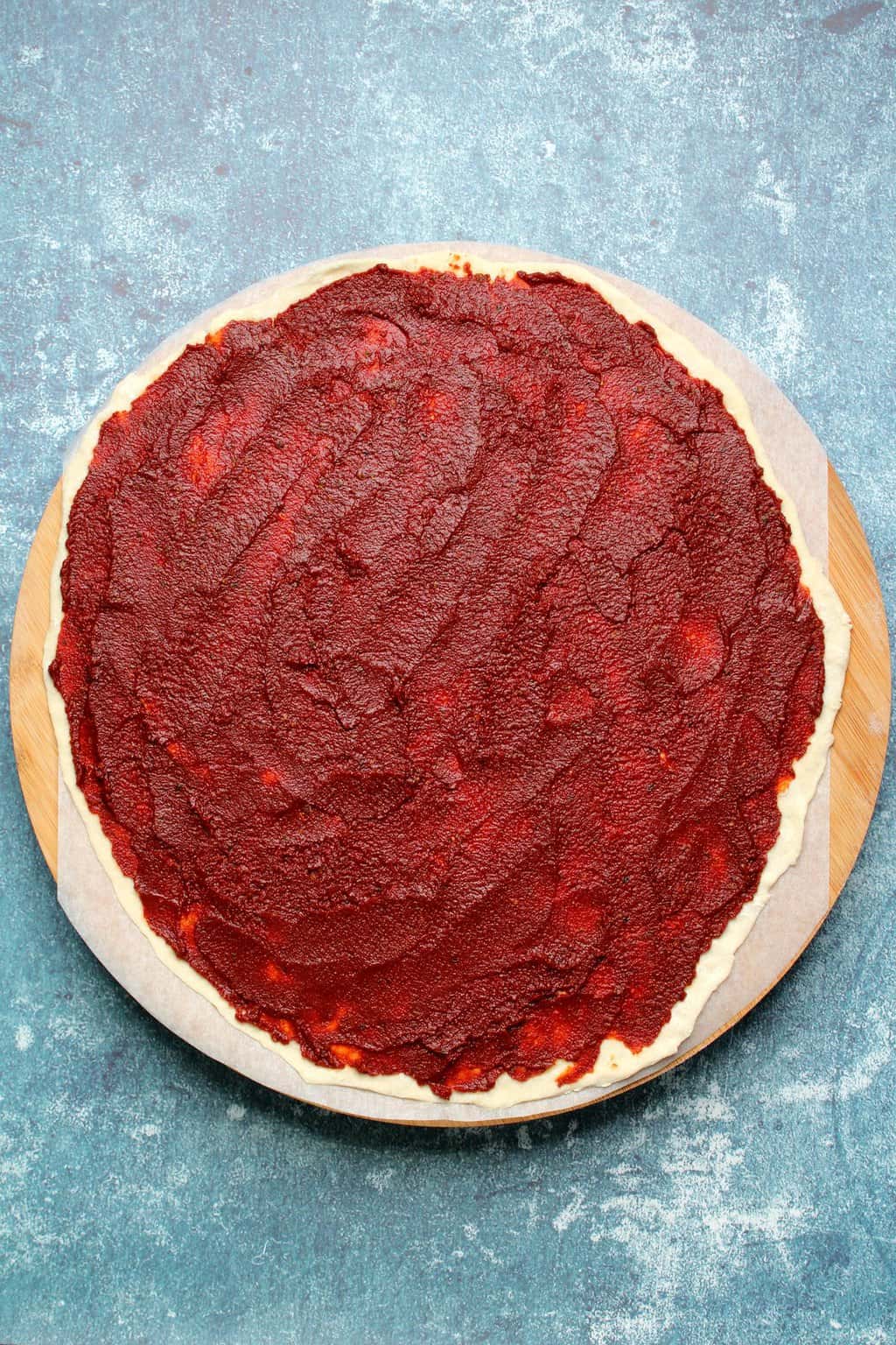 Uncooked vegan pizza base with tomato sauce. 