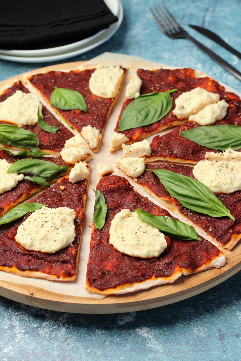 Vegan pizza topped with vegan ricotta and fresh basil leaves. 