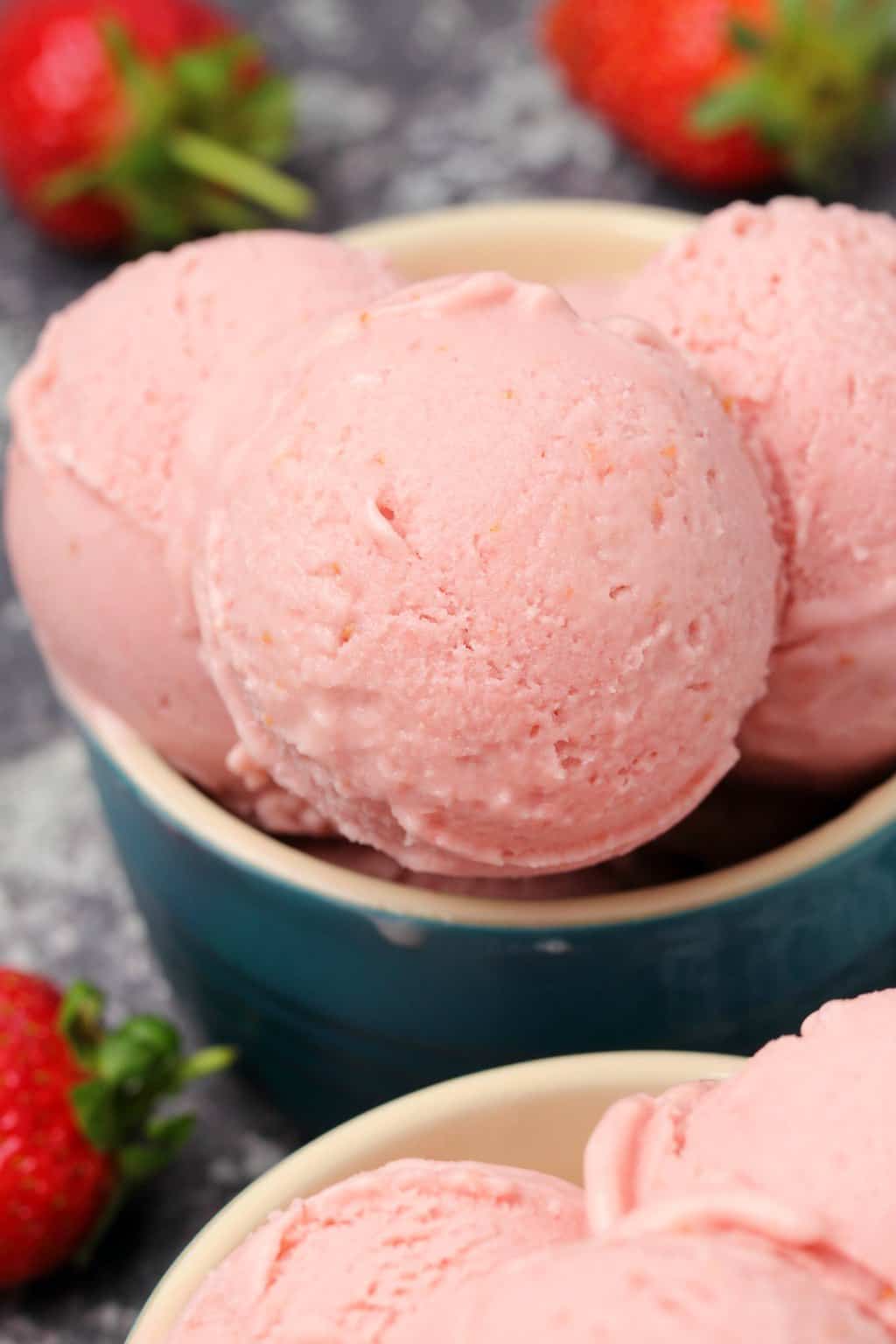 Vegan strawberry ice cream scoops in bowls. 
