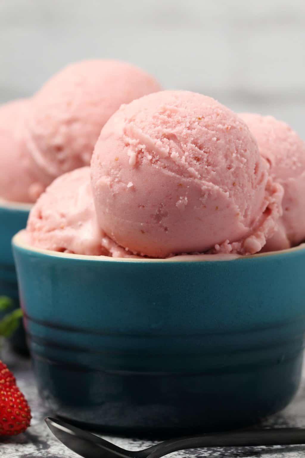 Vegan strawberry ice cream scoops in bowls. 