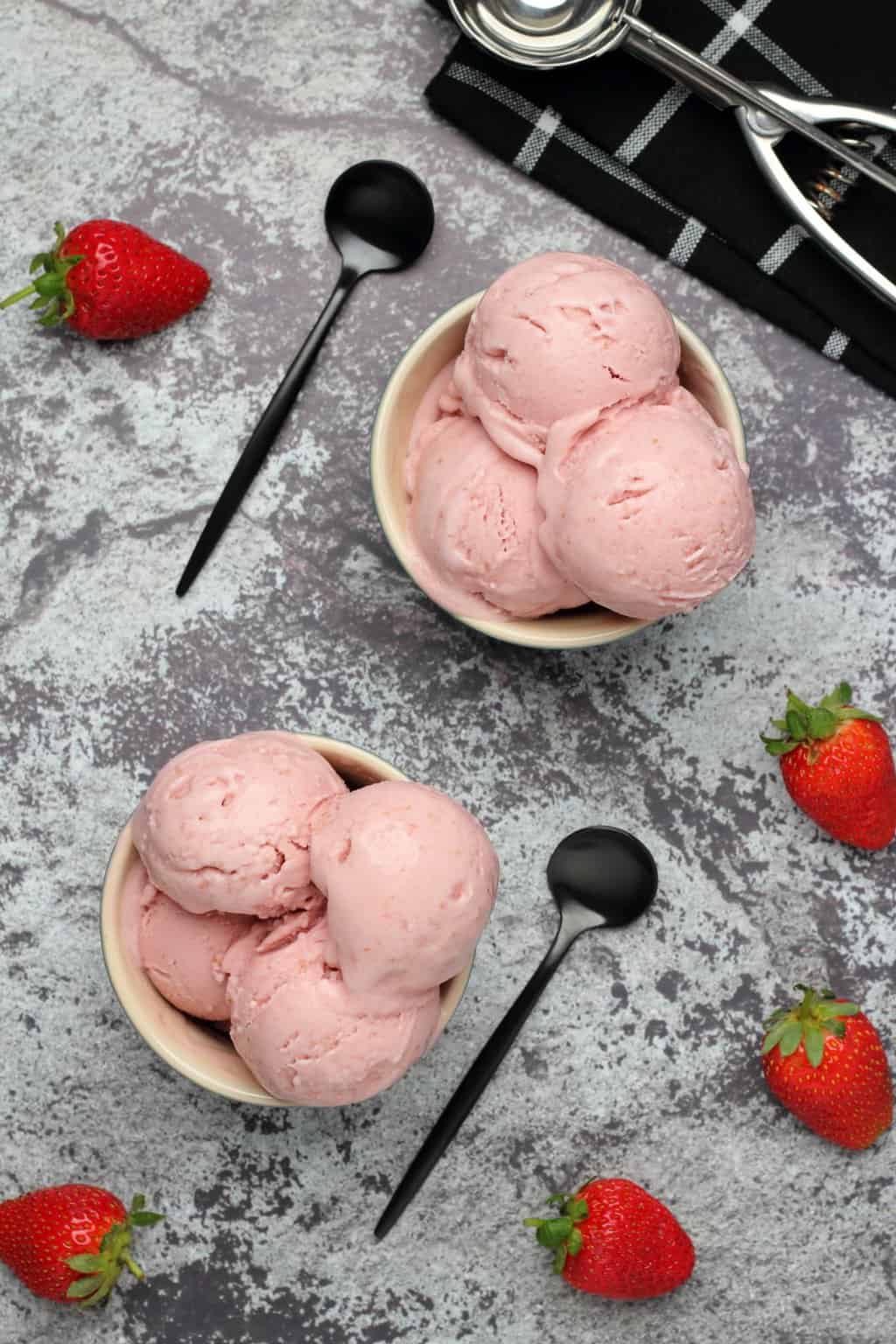 Scoops of vegan strawberry ice cream in bowls. 