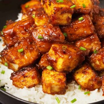 General Tso's Tofu with rice on a black plate.