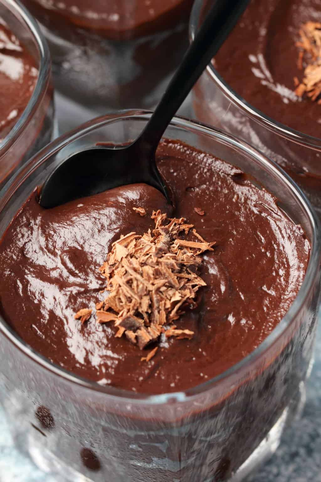 Vegan chocolate avocado mousse in a serving glass with a spoon. 