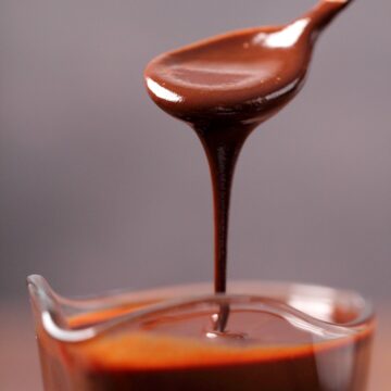 Vegan chocolate sauce drizzling off a spoon.