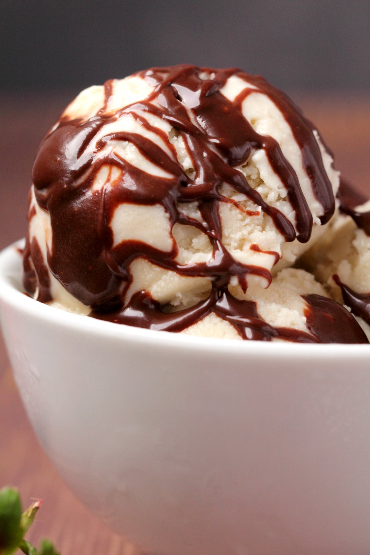  gombóc fagylalt tetején csokoládé öntettel egy fehér tálban. 