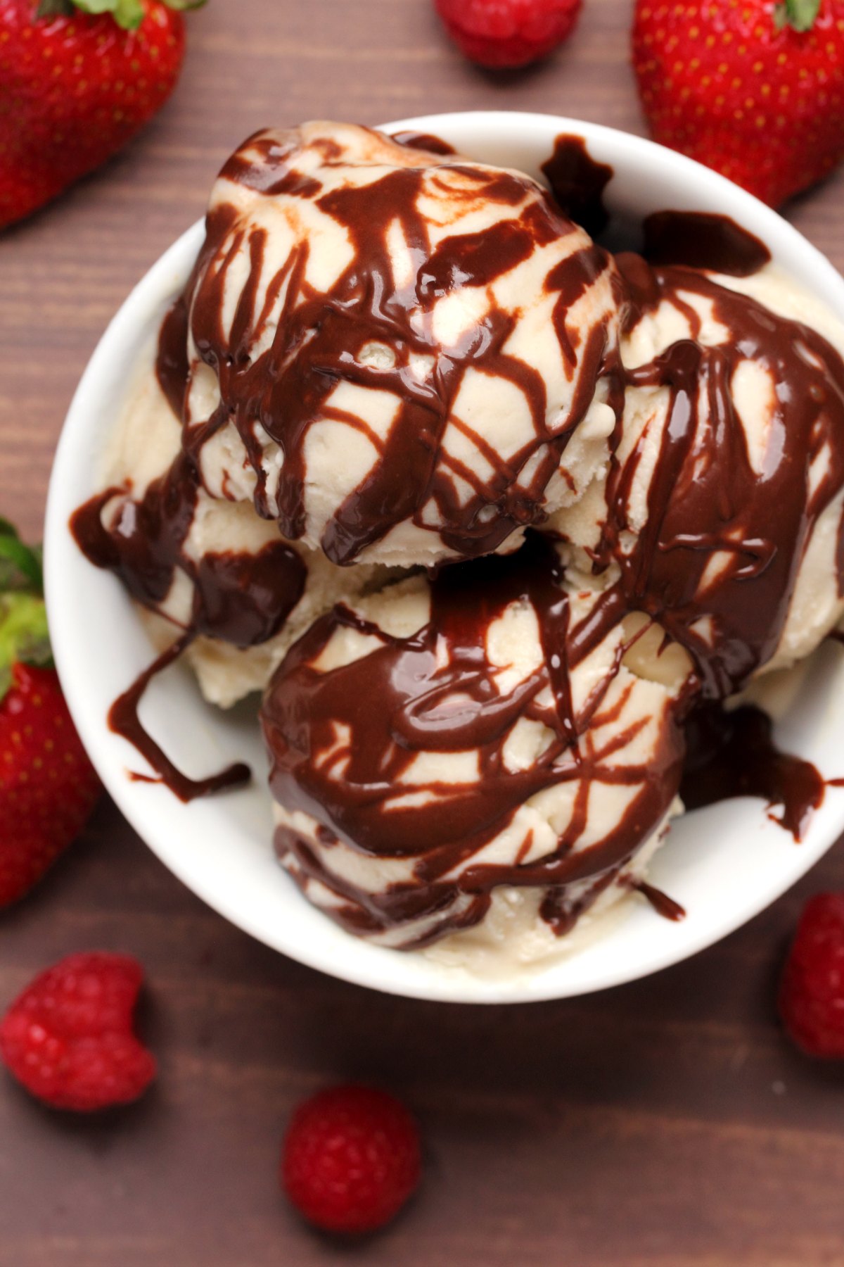 Ice cream drizzled with chocolate sauce in a white bowl. 