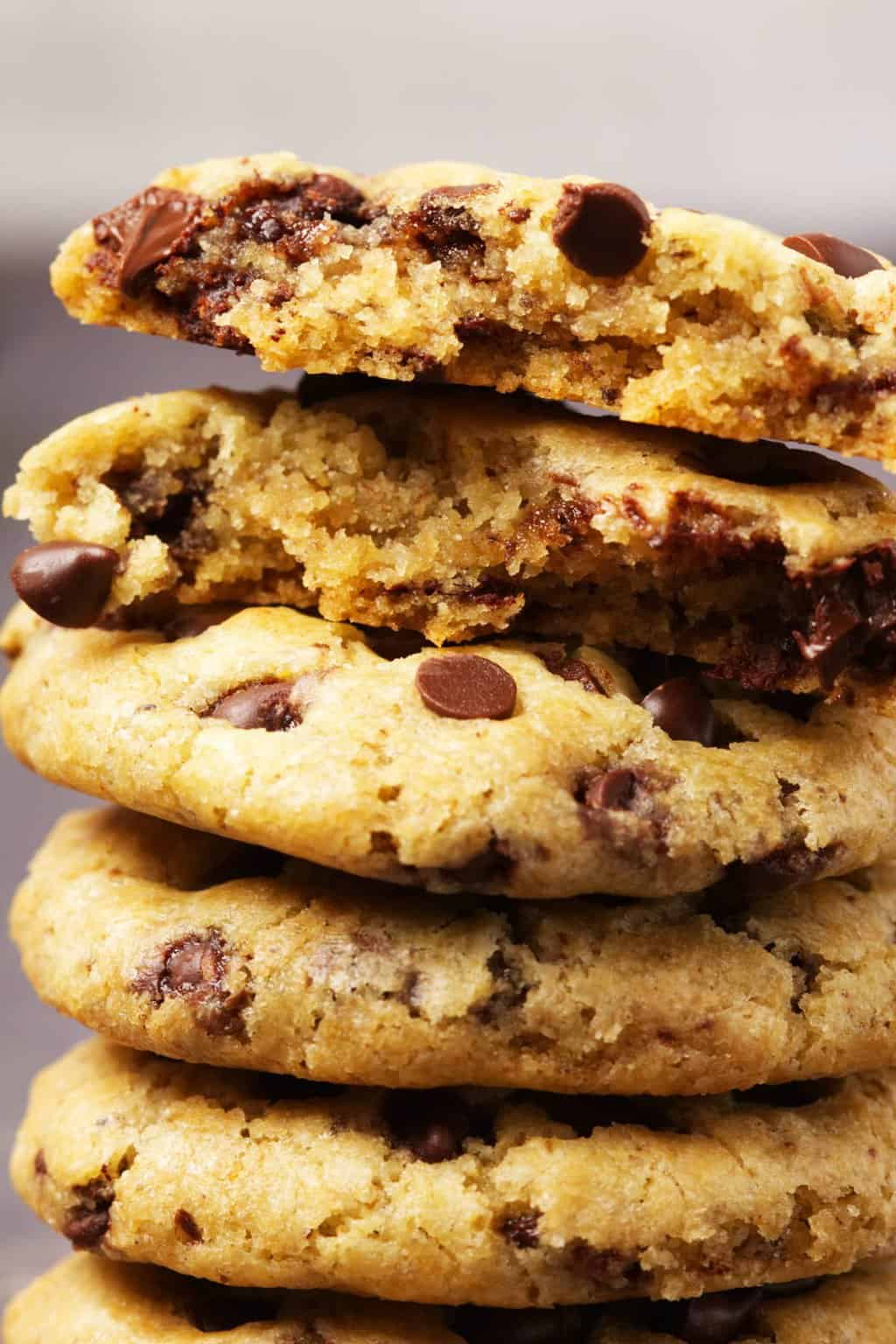 Stack of vegan gluten free chocolate chip cookies with the top cookie broken in half. 