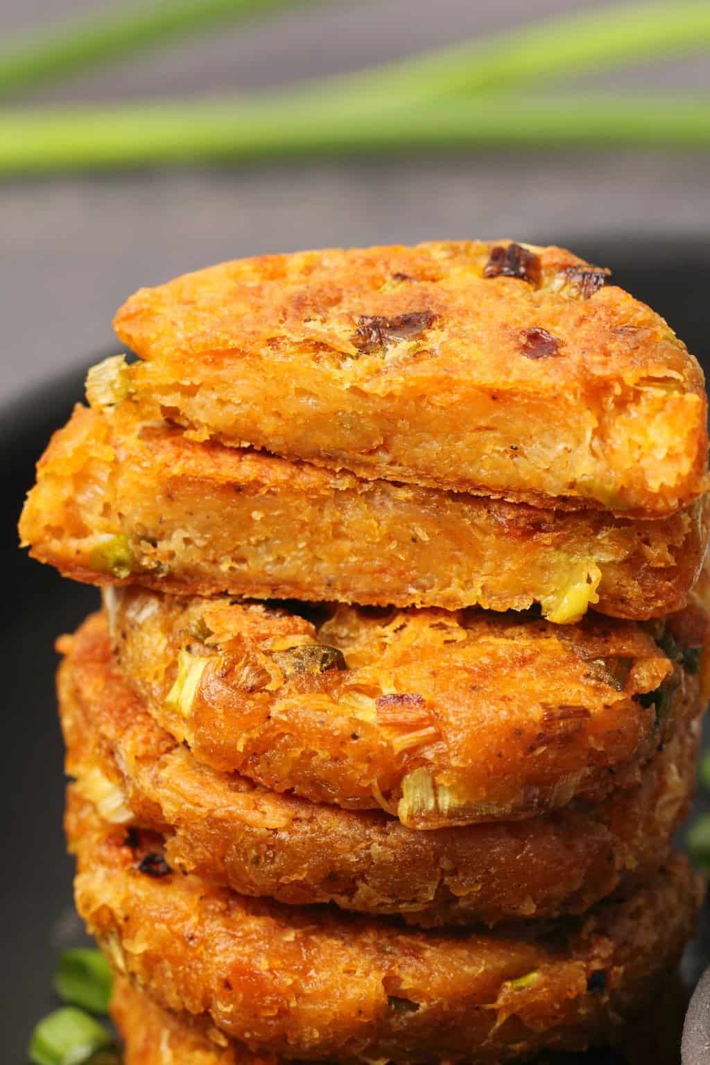 Vegan hash browns in a stack with the top one cut in half to show the center. 