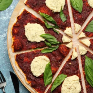 Sliced vegan pizza topped with vegan ricotta and basil.