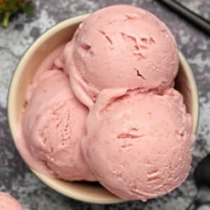 Scoops of vegan strawberry ice cream in a bowl.
