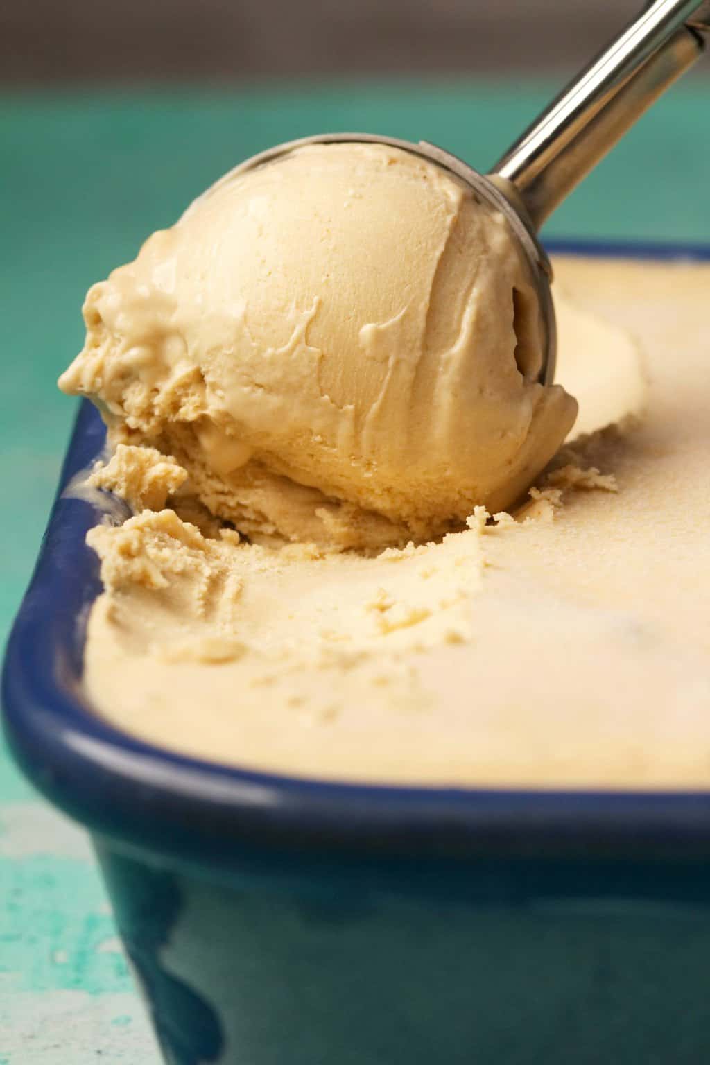 Cashew ice cream being scooped with a silver ice cream scoop. 
