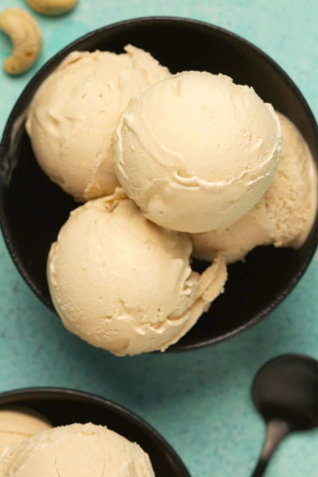 Scoops of cashew ice cream in a black bowl. 