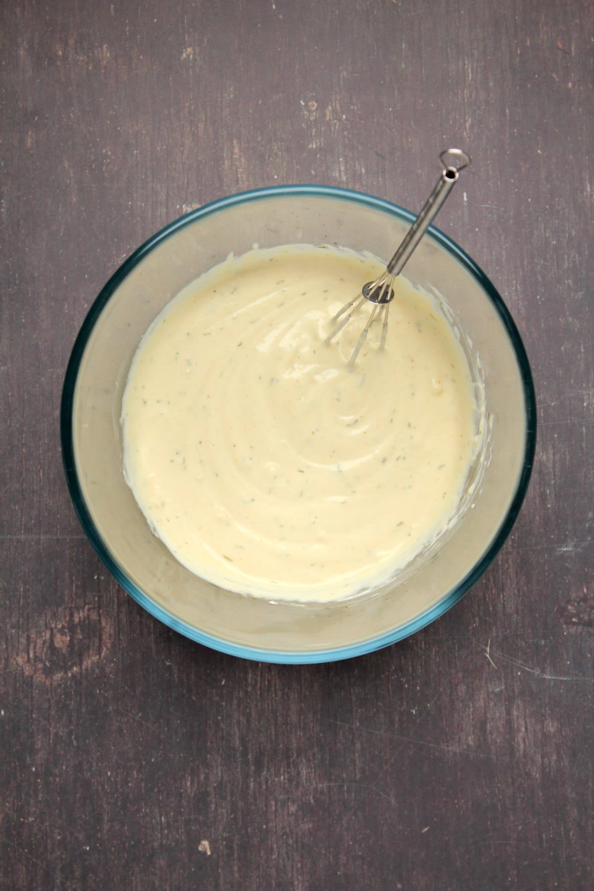 Vegan blue cheese dressing in a glass bowl with a whisk.