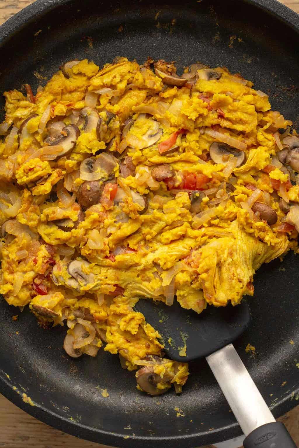 Vegan scrambled eggs in a frying pan with a spatula. 