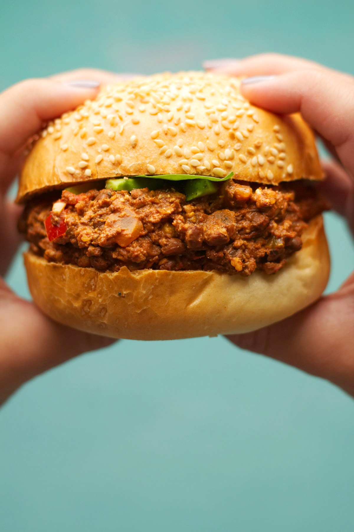 Holding a vegan Sloppy Joe in both hands, ready to take a bite. 