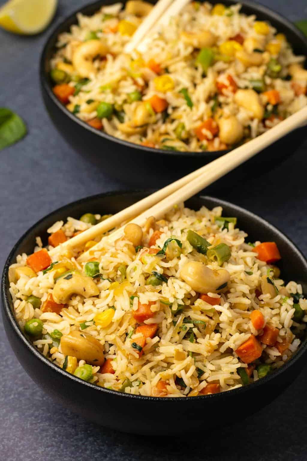 Vegan fried rice in black bowls with chopsticks.
